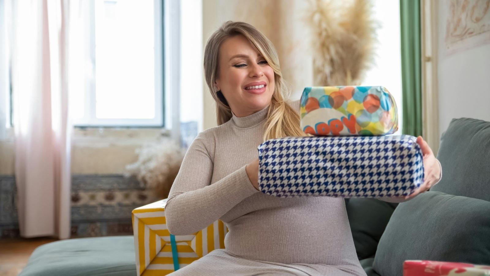pregnant woman holding a stack of gifts