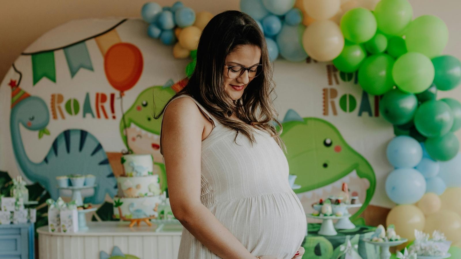 Pregnant woman standing in front of baby shower decorations