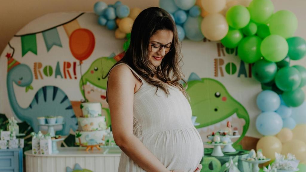 Pregnant woman standing in front of baby shower decorations
