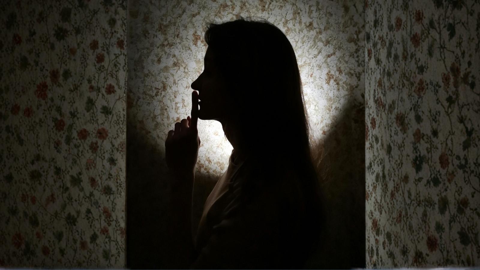 silhouette of a woman holding her finger over her mouth