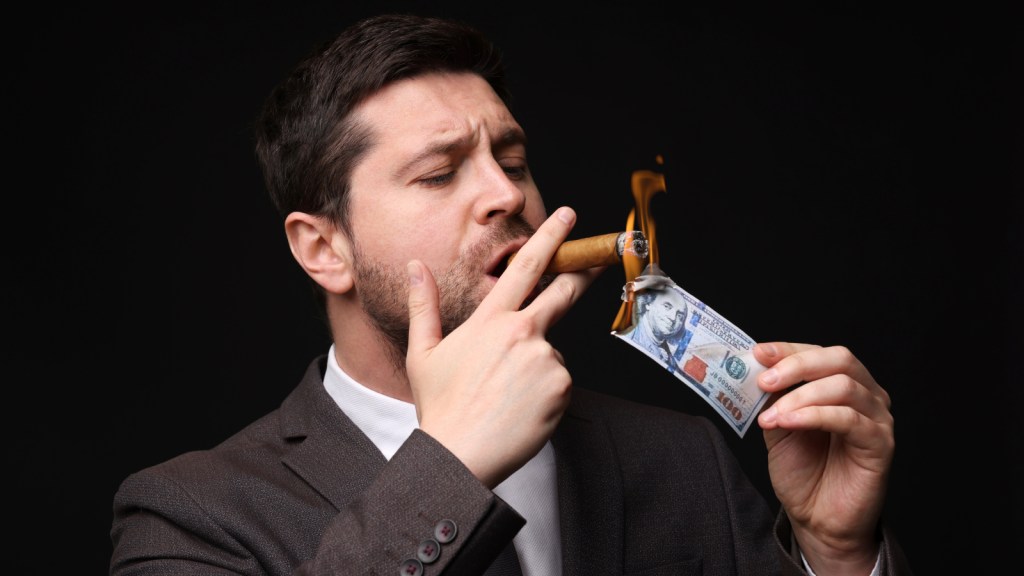 A man lighting a cigar on burning money