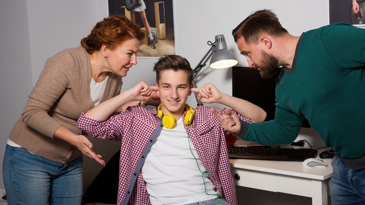 teen boy with fingers in his ears not listening to parents