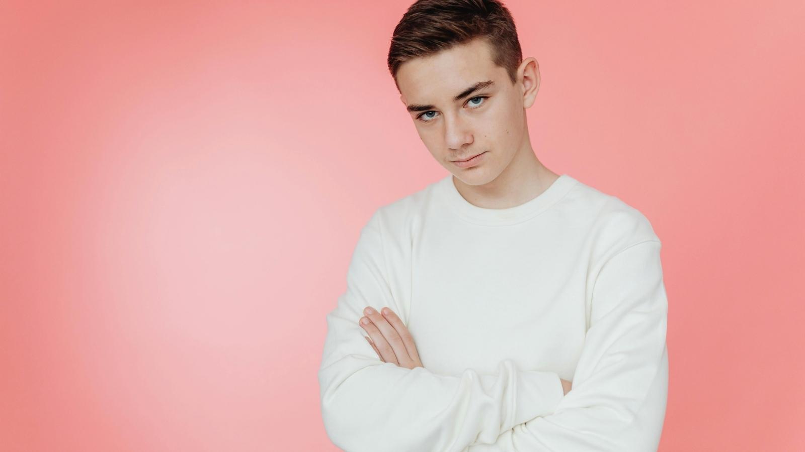 The Cost of Silence: How One Teen’s Discovery of His Sibling’s Theft Has Left Him at a Crossroad teenage boy in white shirt against pink background