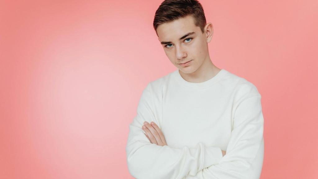 teenage boy in white shirt against pink background