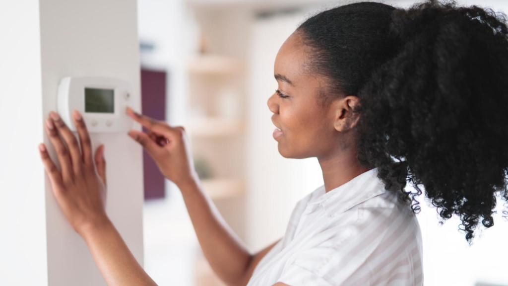 woman adjusting a thermostat