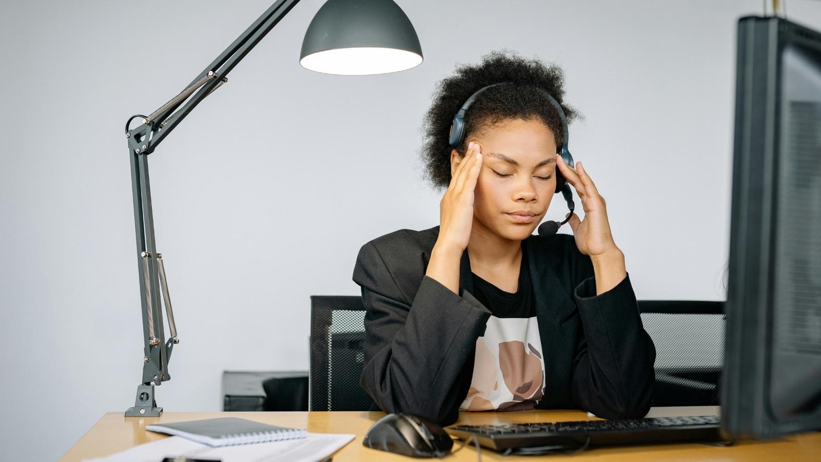 upset woman covering her face at her desk