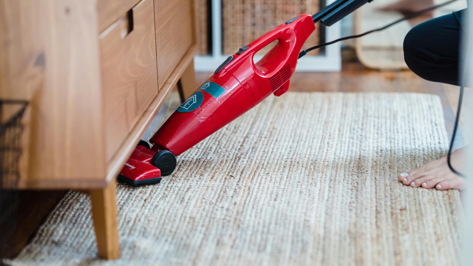 someone vacuuming under furniture 