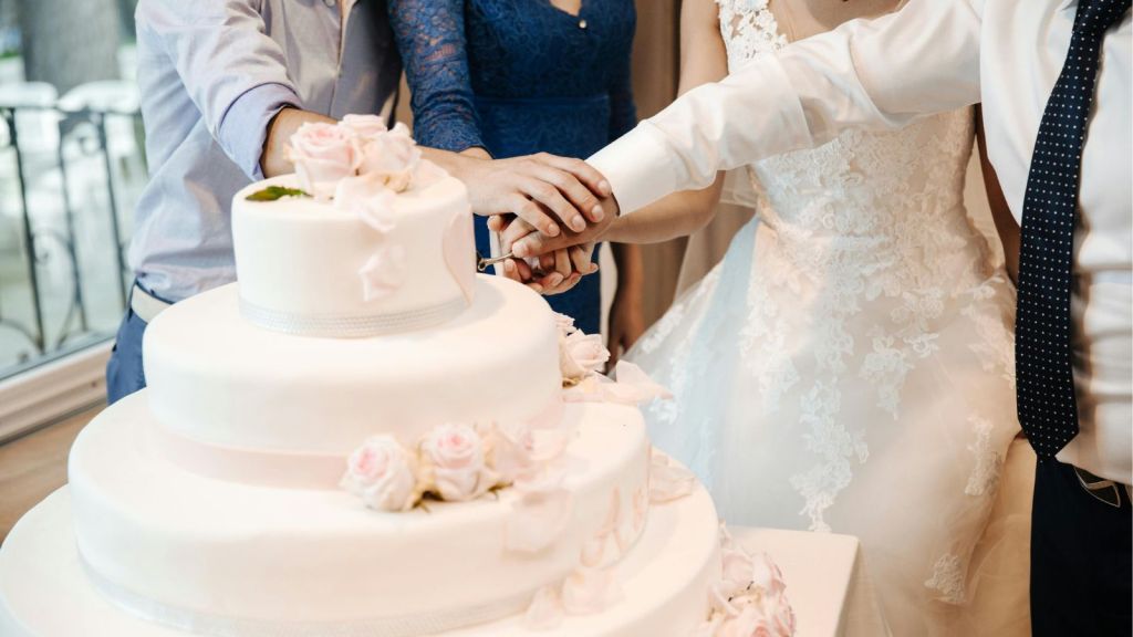Newlyweds and guests cutting a wedding cake