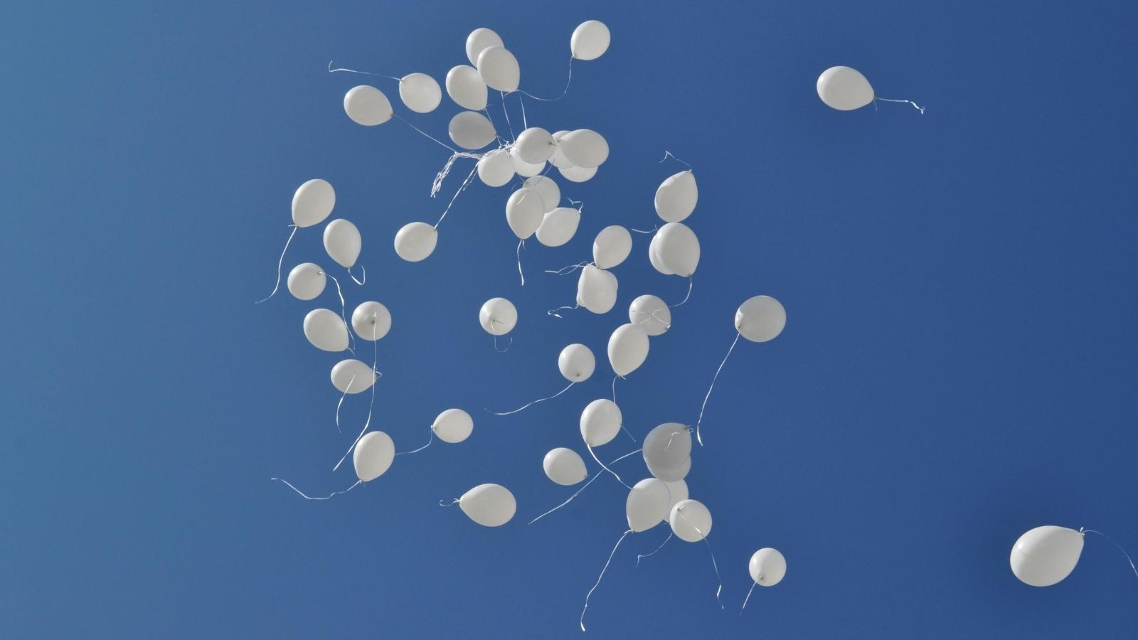 Employee Raises Environmental Concerns About Memorial Balloon Release, Then Gets Shut Down by Boss white balloons floating in a blue sky