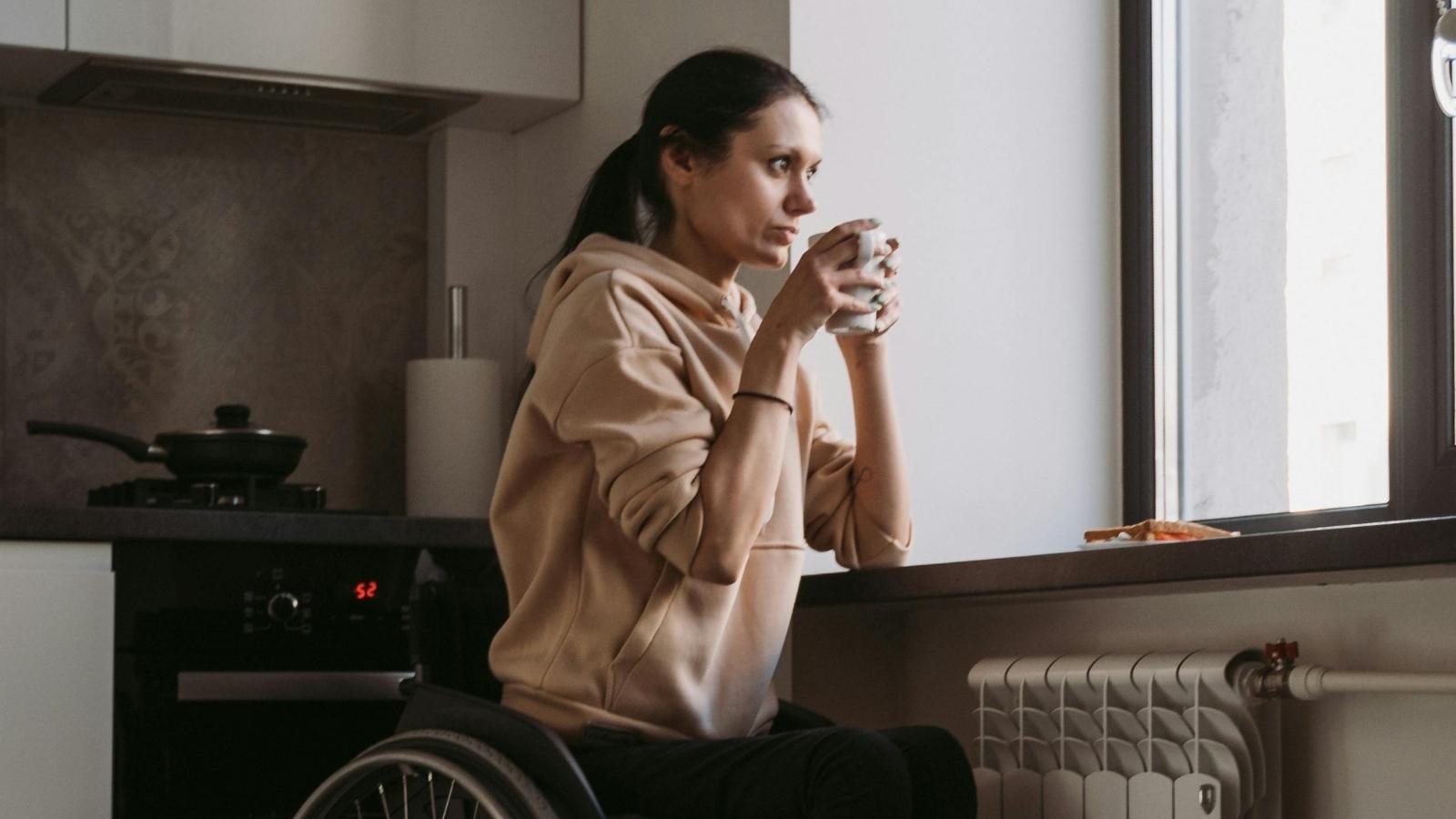 Wheelchair User Questions Friendship After Best Friend Makes Offensive Comment About Disability woman in wheelchair sitting by the window