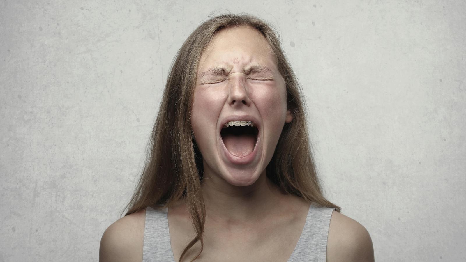 woman yelling against grey background