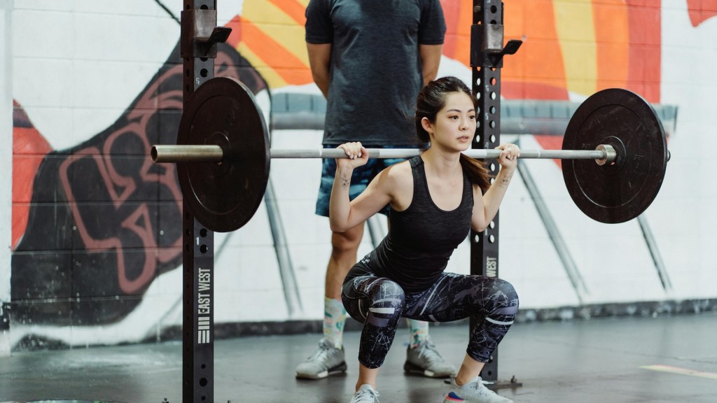 young woman using a large dumbbell/barbell