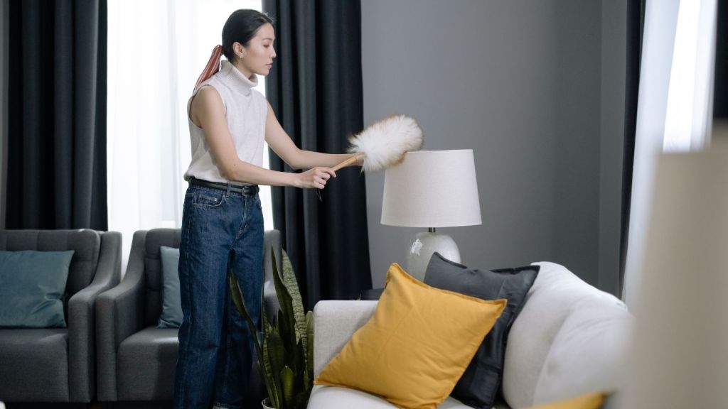A woman cleaning with a feather duster
