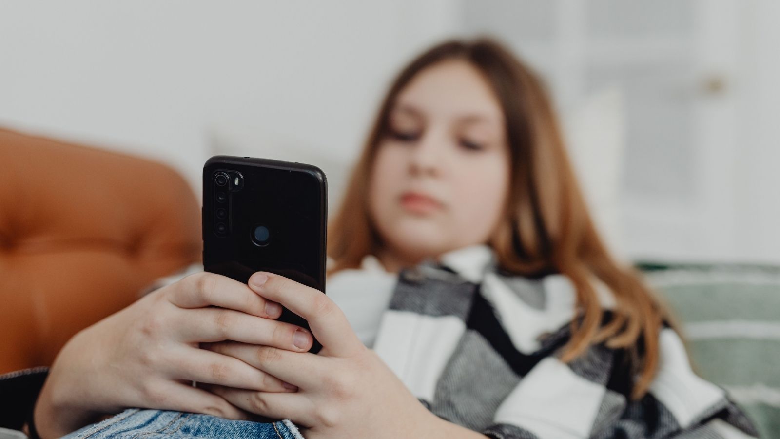 A teen scrolling on the couch
