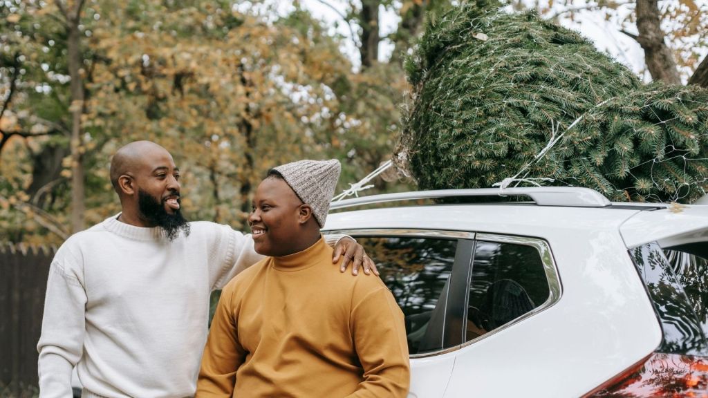 A couple with a Christmas tree on their car