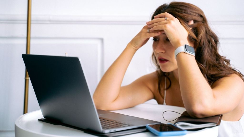 A woman at her laptop with her head in her hands