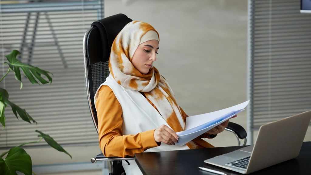 A woman in a hijab working at her desk