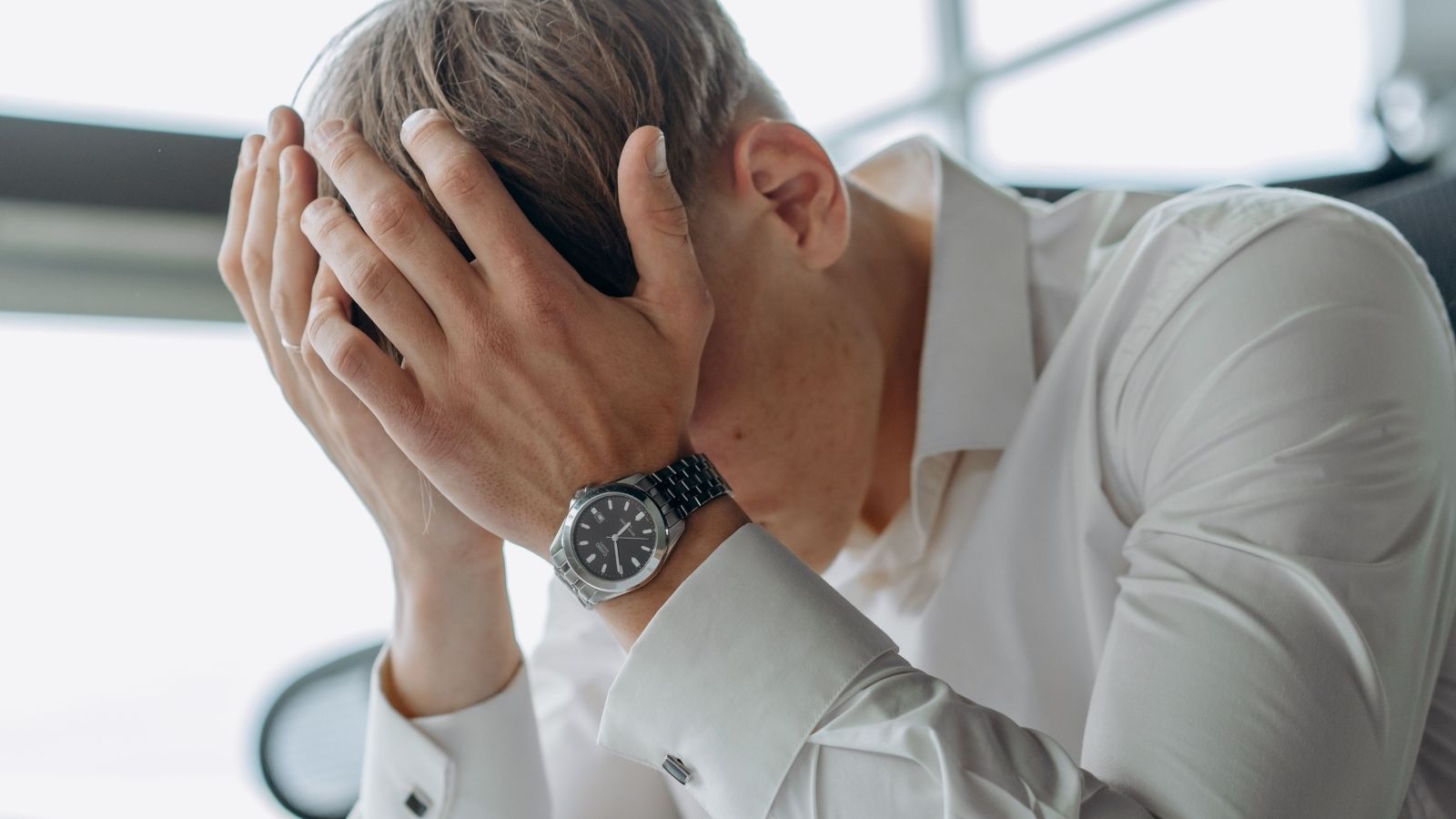 Employee Just Wants to Work and Go Home, but Talkative Customers Have Other Plans An employee with his head in his hands