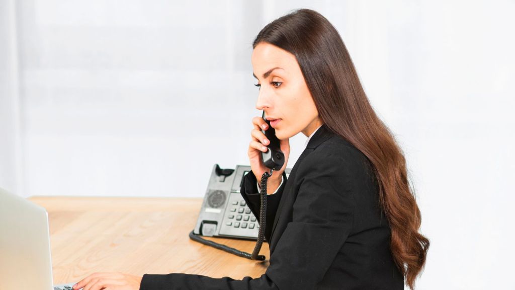Female receptionist taking a call while looking at her computer