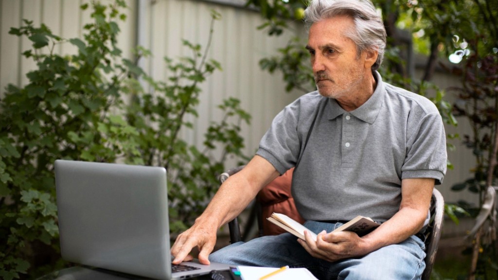 Older man using a laptop outside