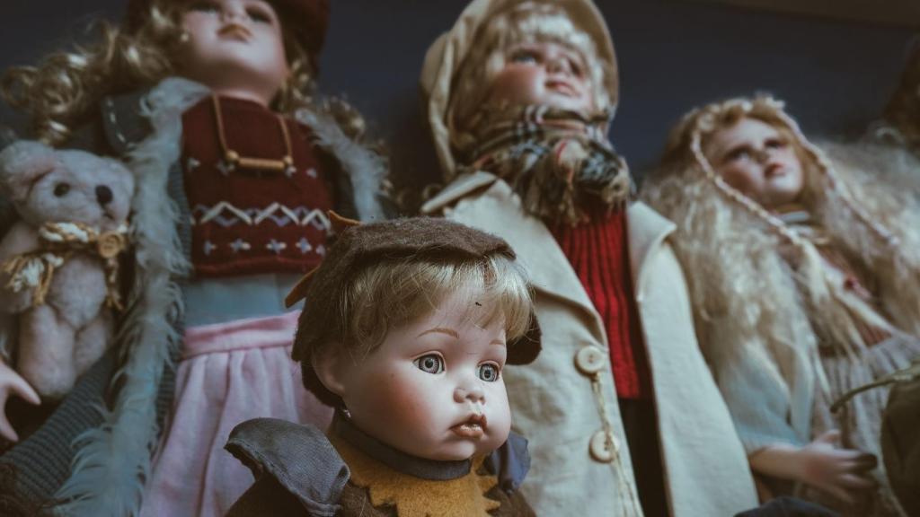 Collection of dolls standing by a wall
