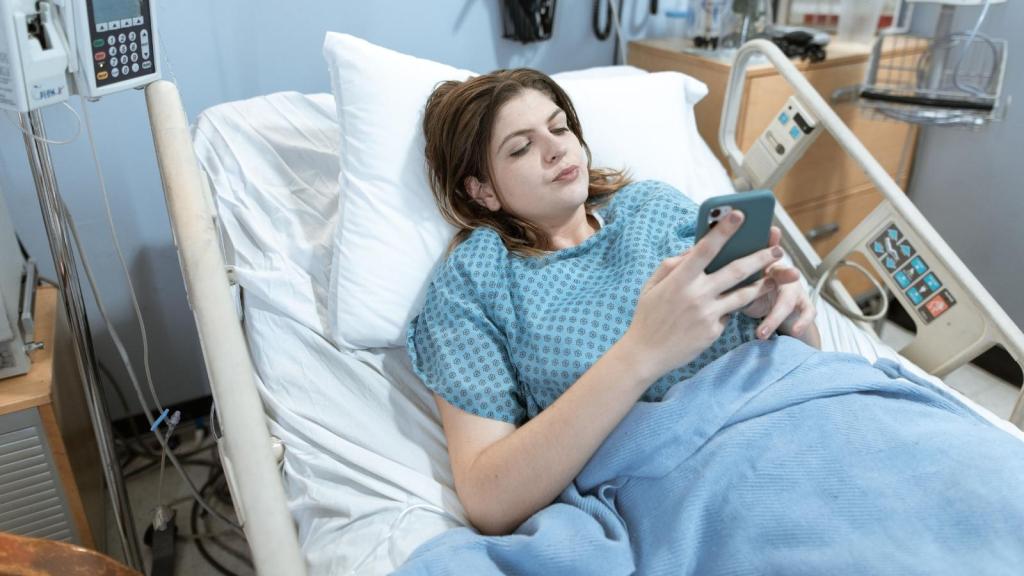 Young woman on her phone in a hospital bed