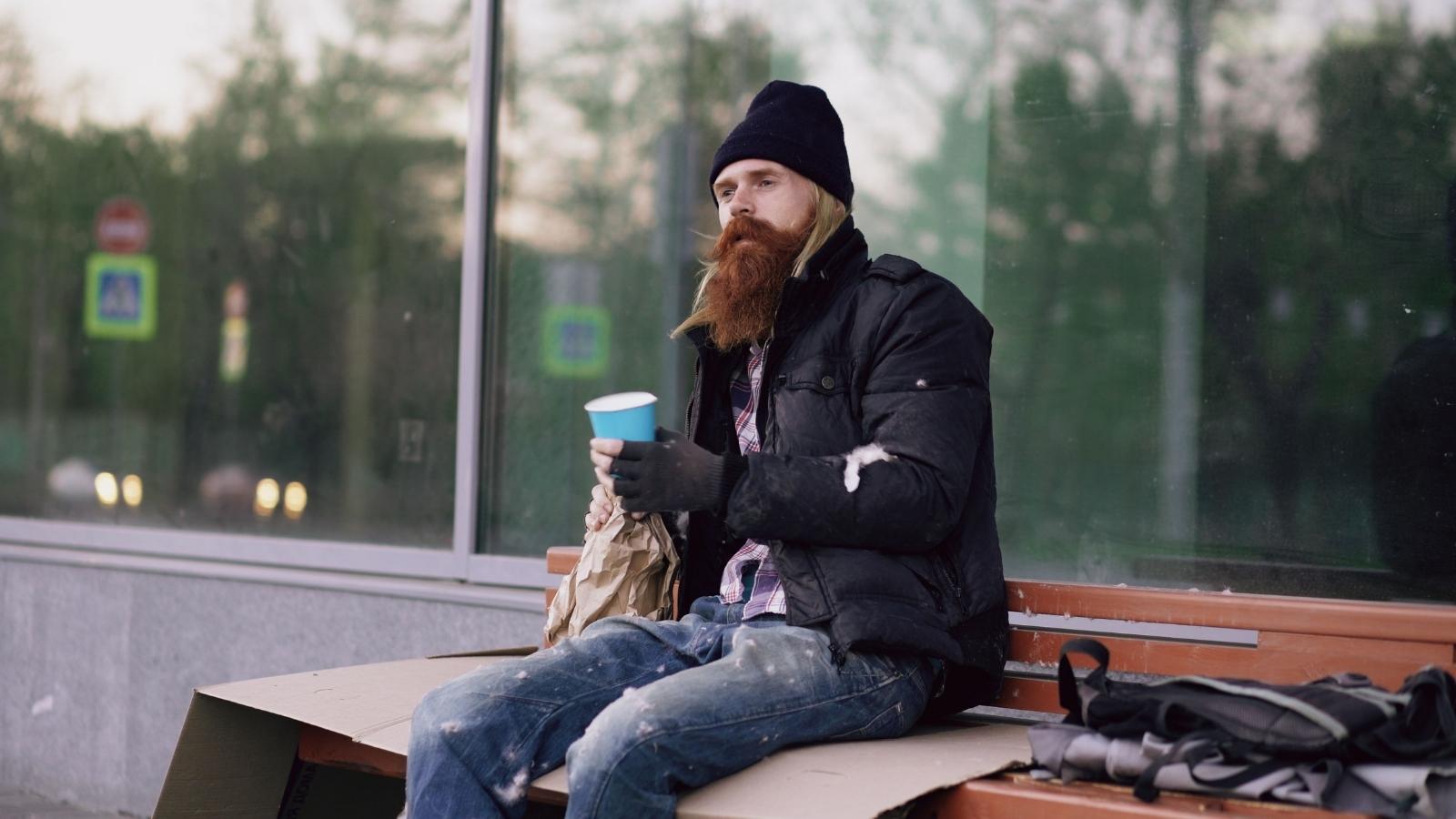 Bystander Calls Out Influencer Couple Filming Homeless Man During Charity Gesture Homeless man sitting in front of a business