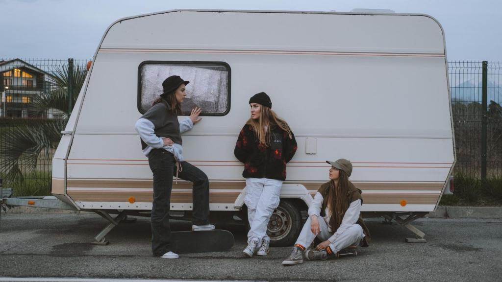 Three women leaning against a camper