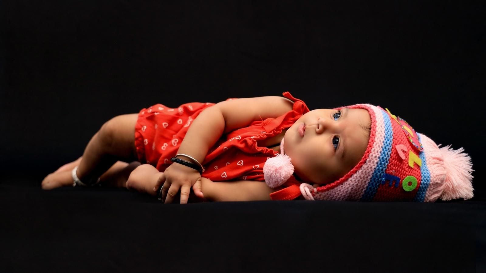 Little infant laying on a black background