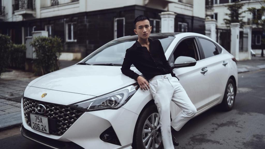 Asian man standing against his car