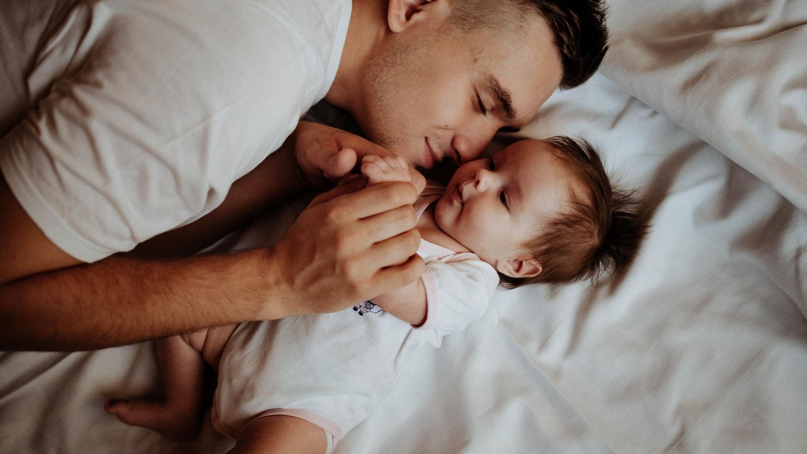New Father Declines to Help Former Roommates Move, but They Accuse Him of Not Returning the Favor After Years of Helping Him Man snuggling his newborn son on a bed