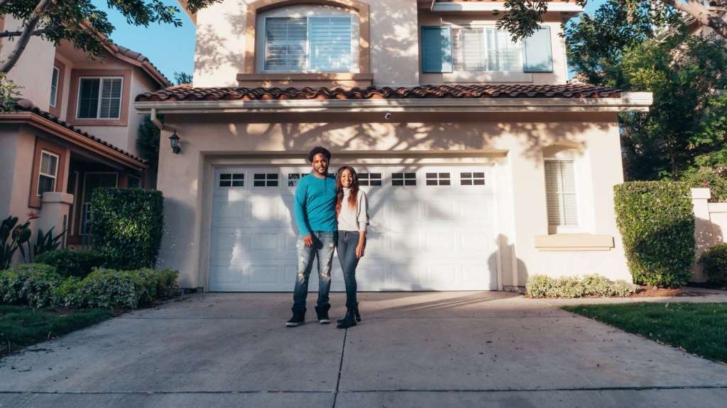 Couple standing out front their home