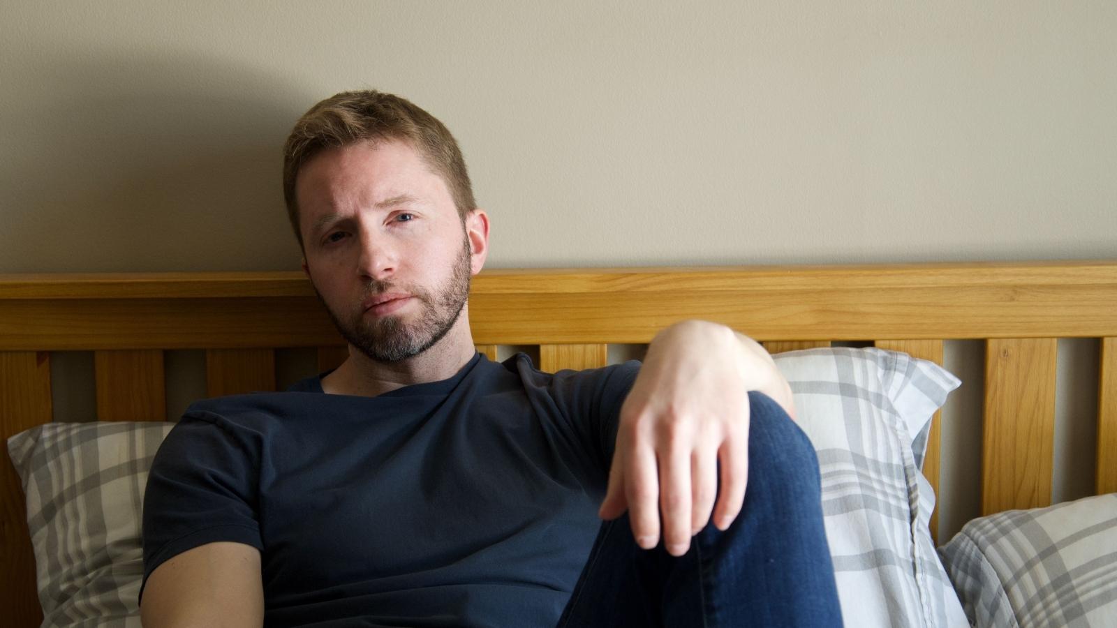 Man sitting on bed thinking about his situation