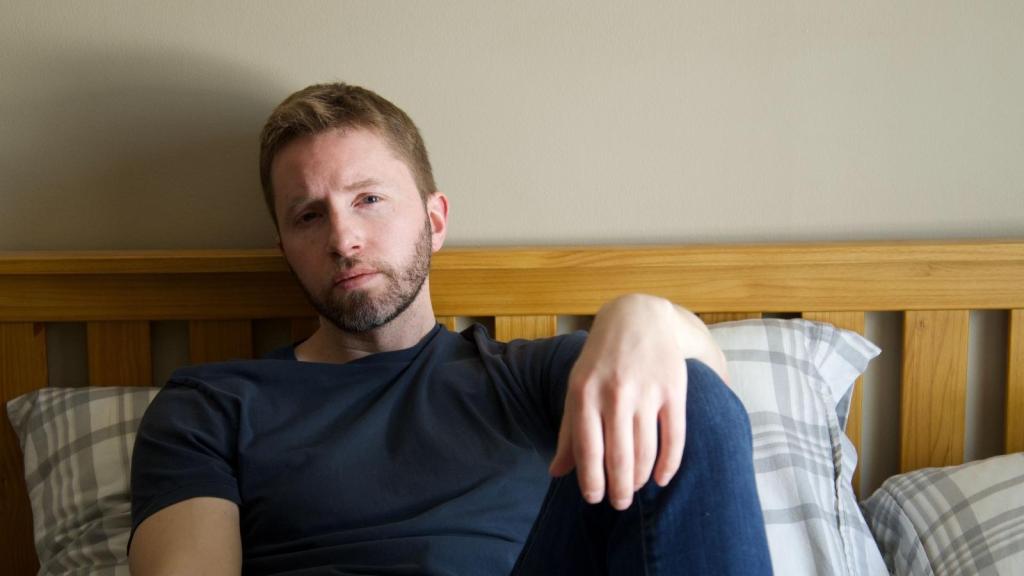 Man sitting on bed thinking about his situation