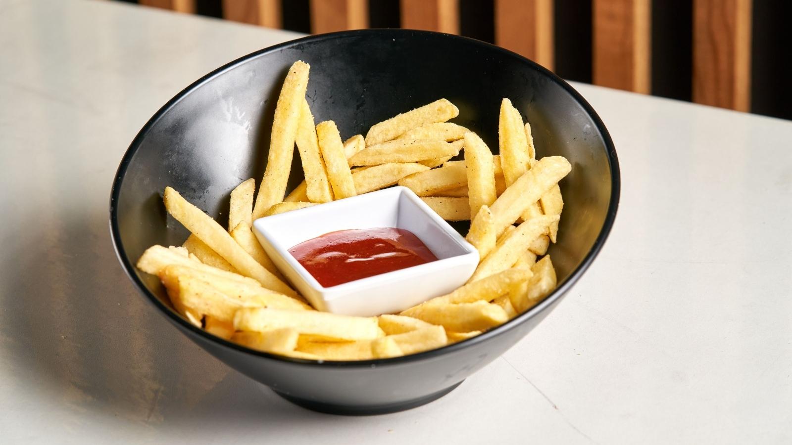 Bowl of french fries and a serving of ketchup