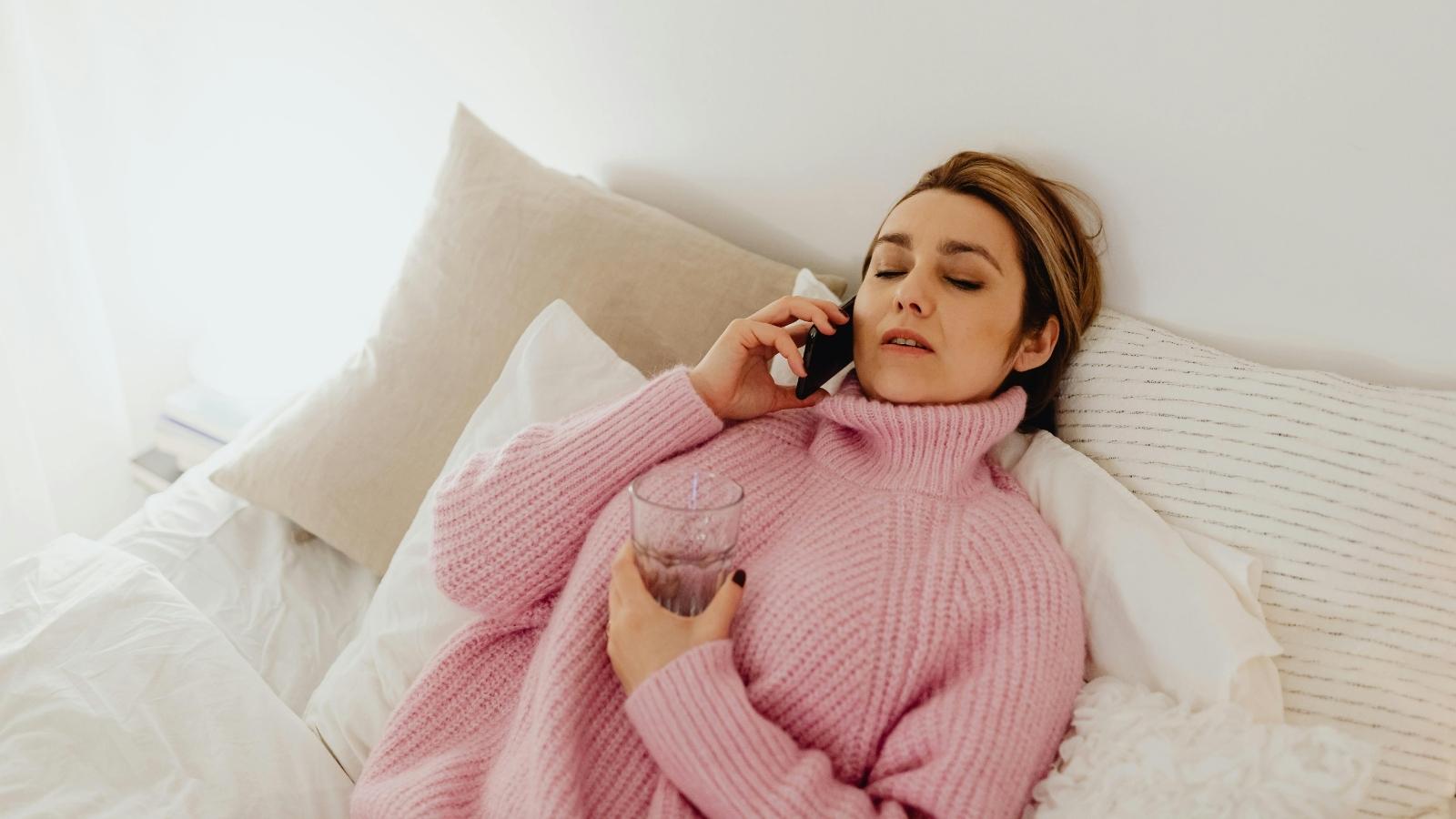 Retail Employee Tries to Tough Out a Virus During a Holiday Blackout Period, but a Manager Complains That Her Vomiting Is Making Customers Uncomfortable Woman sick and laying on her bed.