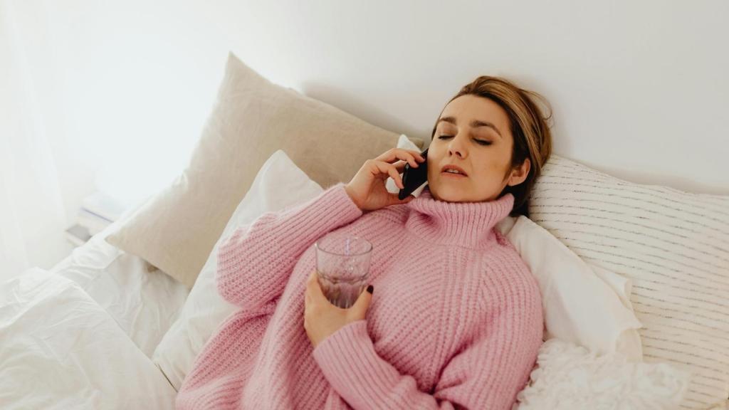 Woman sick and laying on her bed.