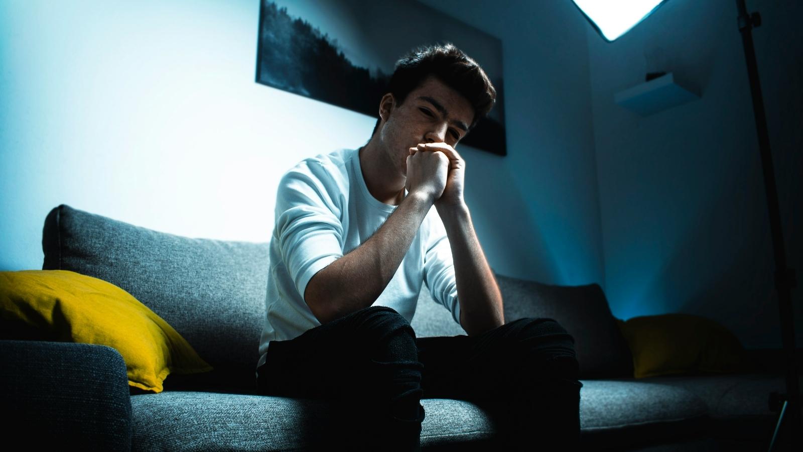 Man Faces Backlash For Telling His Brother’s Boyfriend the Truth About His Health troubled man sitting on couch