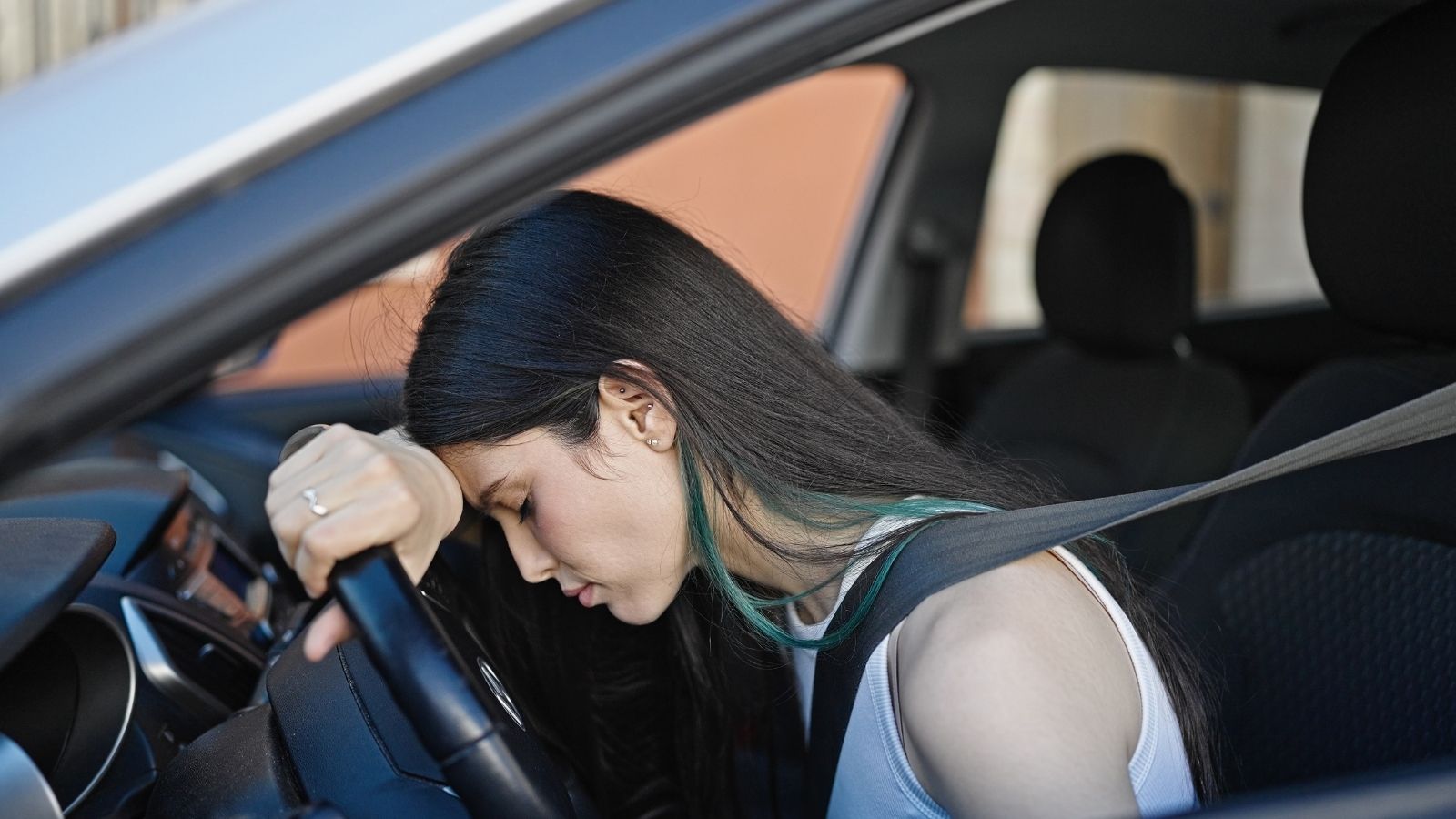 Mom Sparks Bitter Family Argument After Banning Daughter From Charging Sibling for Gas upset young woman in the drivers seat of a car