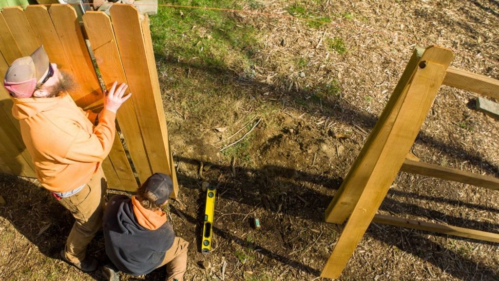 two construction workers building a fence