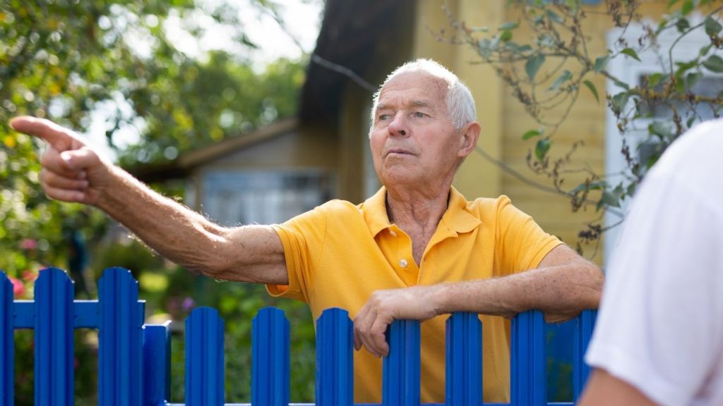 elderly man pointing while talking to his neighbor