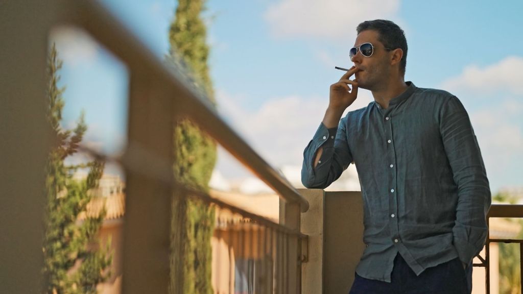 man standing on a balcony smoking