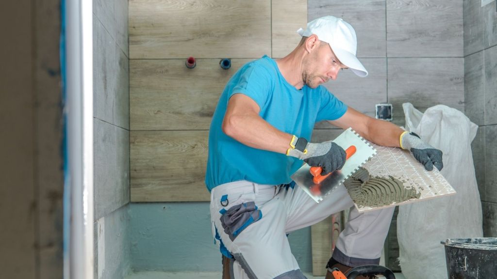 man installing tile in a bathroom