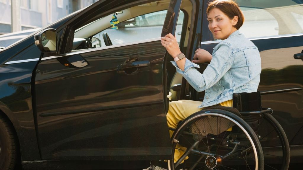 woman in a wheelchair getting in her car