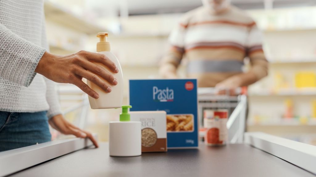 closeup of woman's hand putting products on grocery store conveyor belt
