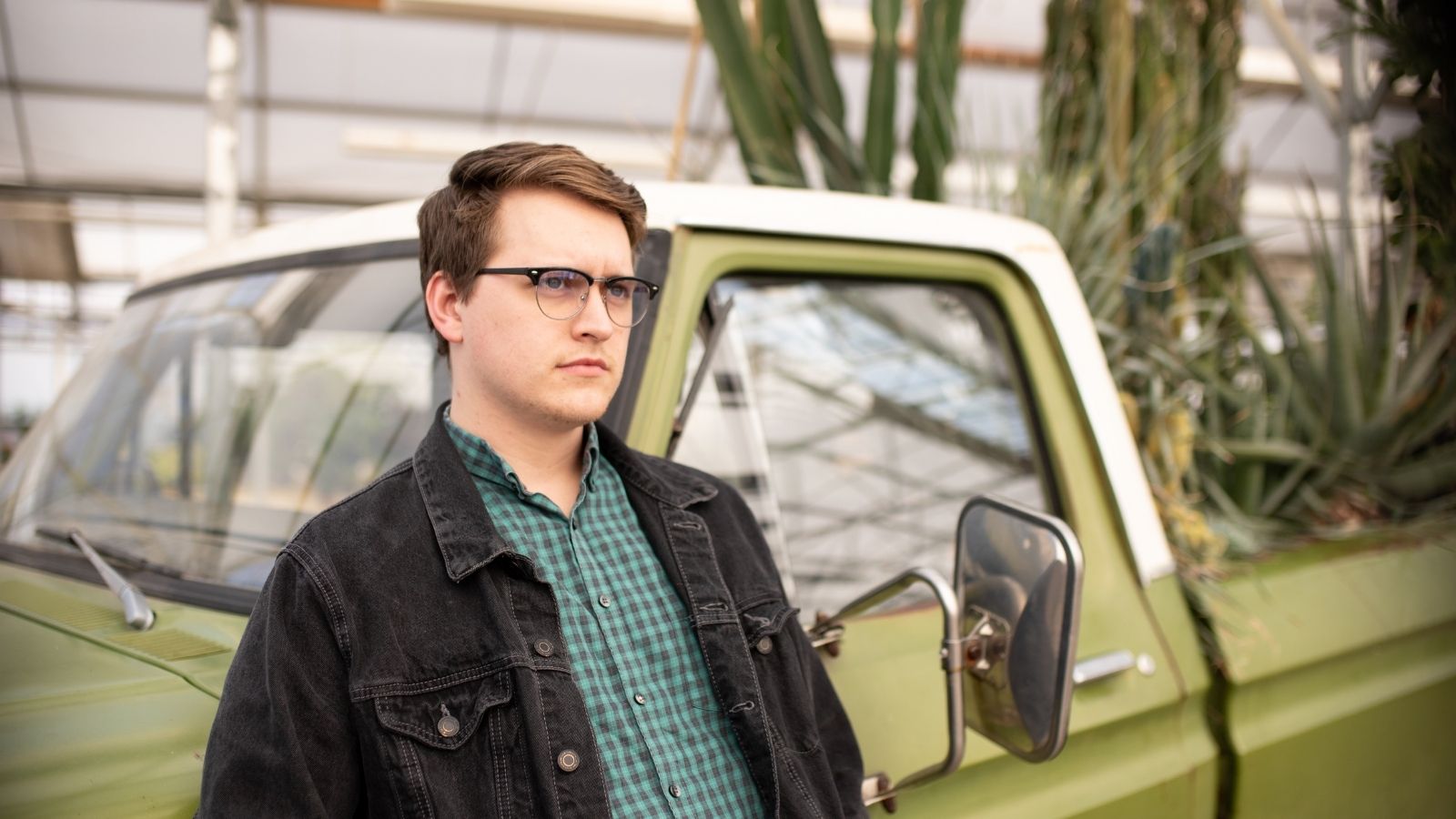 man leaning against older green truck
