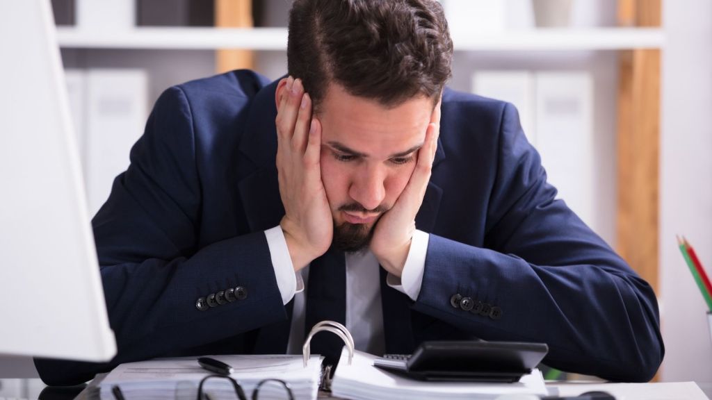 unhappy businessman looking at paperwork and calculator