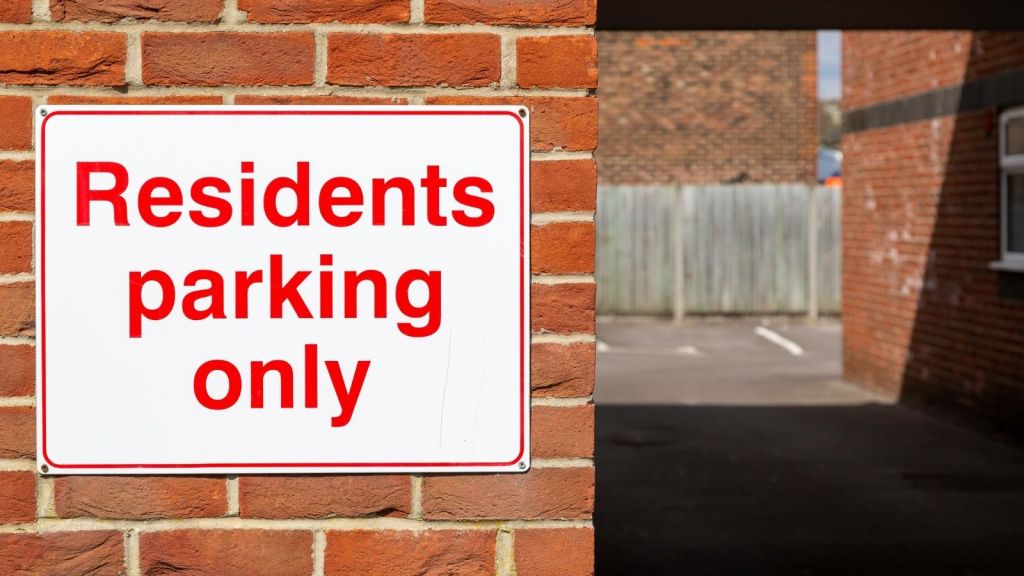 sign on a brick wall that reads "residents parking only"