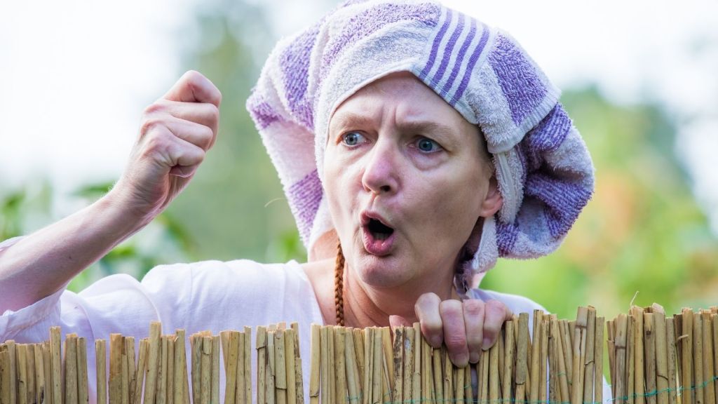 angry woman with a towel on her head yelling over a fence