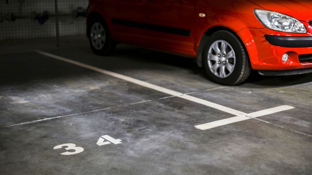 red car parked next to an open parking spot with "34" painted on it